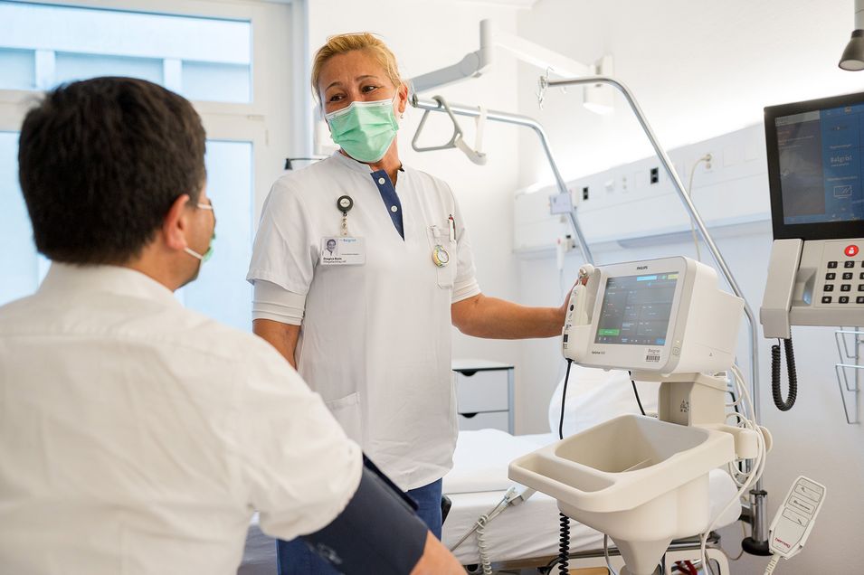 Eine Pflegemitarbeitende im Gespräch mit einem Patienten.