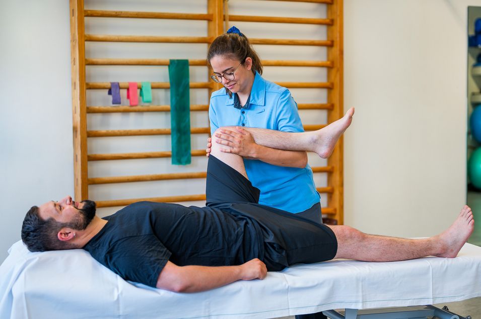 Behandlung der Kniebeschwerden in der Physiotherapie. Physiotherapeutin behandelt das Knie des Patienten auf der Liege.