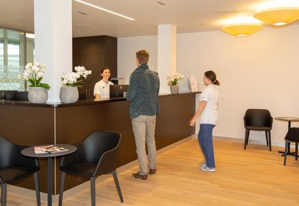 Der Empfang der Tagesklinik Zwei Personen werden am Empfang der Tagesklinik empfangen