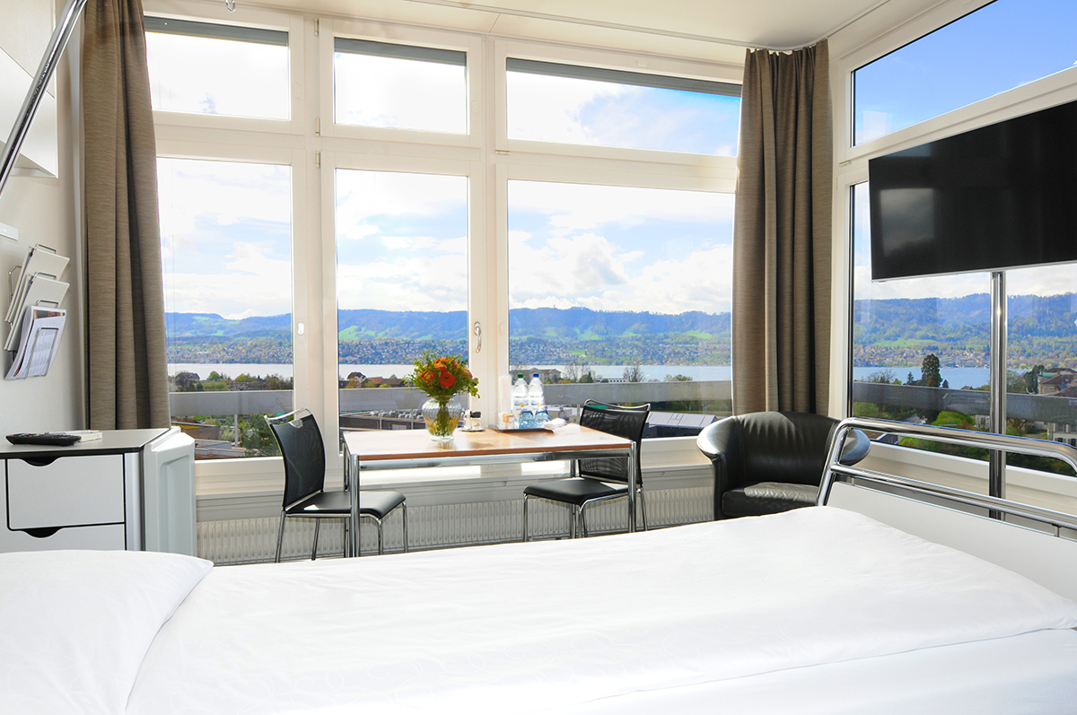 Balgrist-Privatzimmer mit Blick auf den Zürichsee Bett im Vordergrund eines Privatzimmers mit Blick auf den Zürichsee.